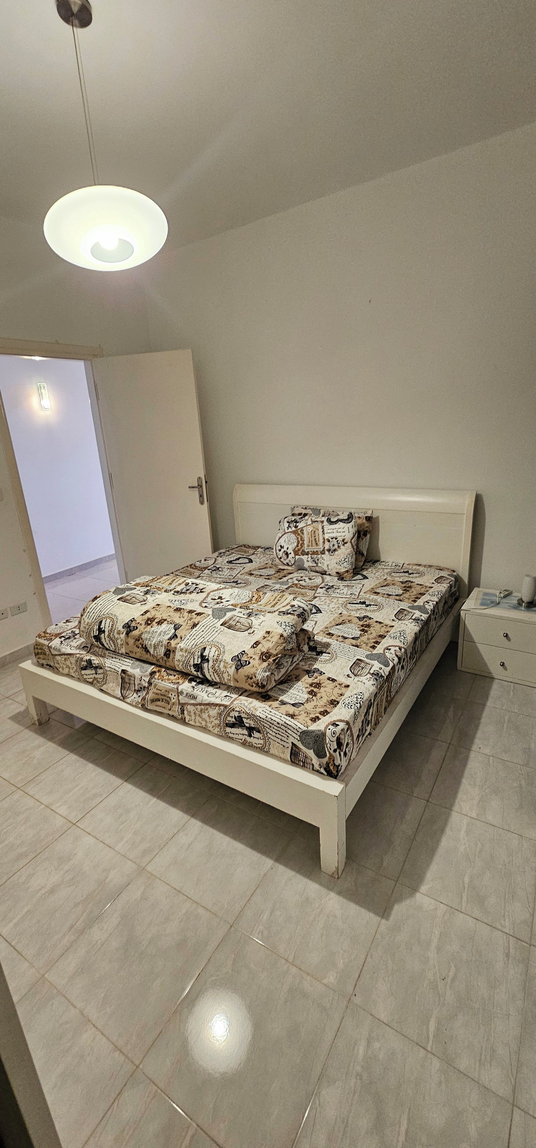 Een slaapkamer met een bed, een nachtkastje en een deur.