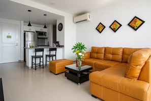A modern living room with a sofa, a coffee table, and a kitchen area in the background. - Comfortable Apartment near the sea in Cartagena (Cartagena)