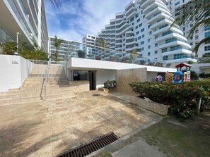 A modern building with a staircase leading to a gated entrance, a small garden area with a children's play structure, and a clear sky. - Comfortable Apartment near the sea in Cartagena (Cartagena)