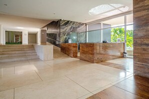 A spacious lobby with a marble reception desk, a staircase, and a large window providing a view of greenery. - Comfortable Apartment near the sea in Cartagena (Cartagena)
