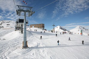 Eine Skipiste mit Skilift, einem Holzbau und Skifahrern.