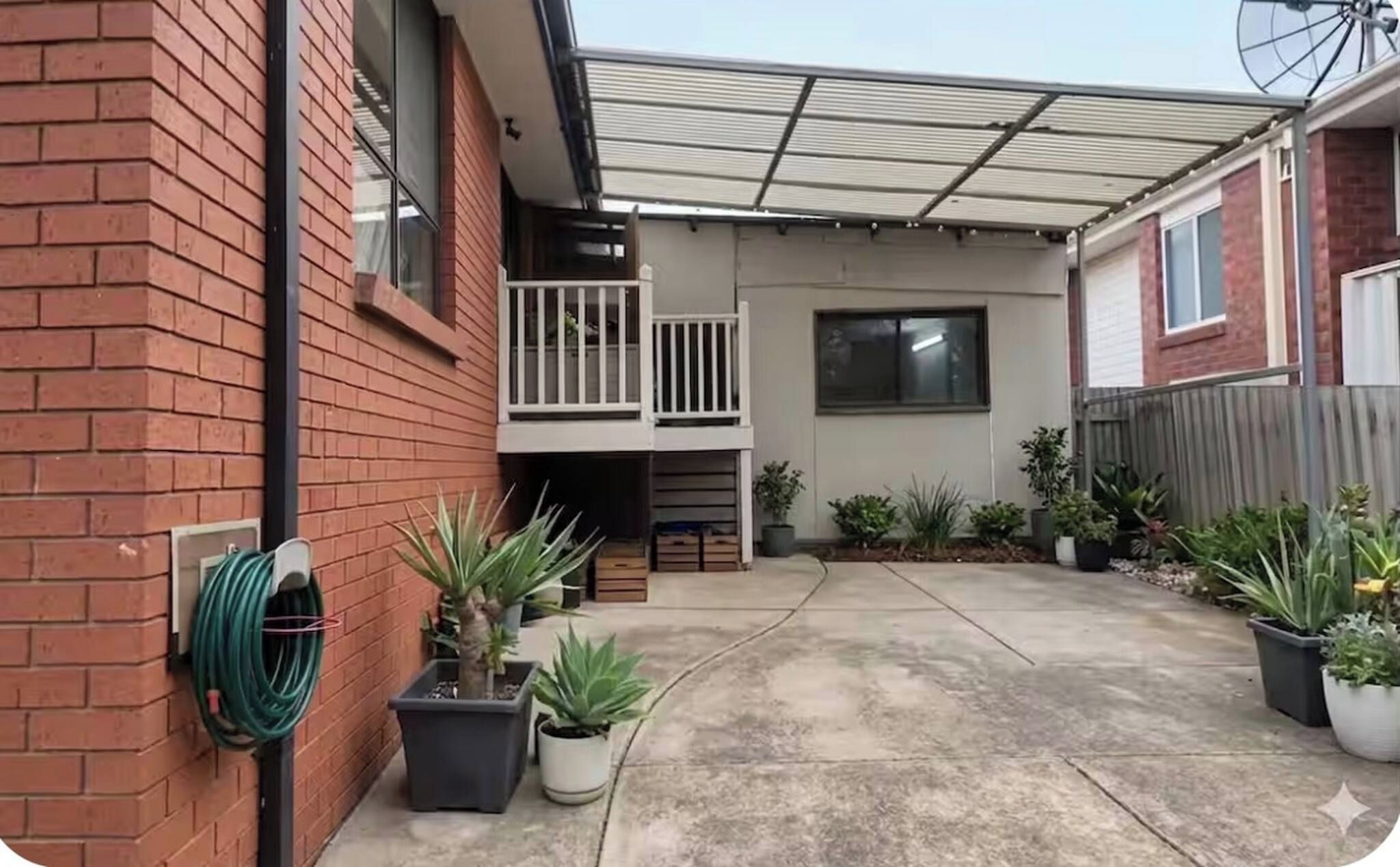 A residential property with a covered patio, a brick wall, and potted plants.