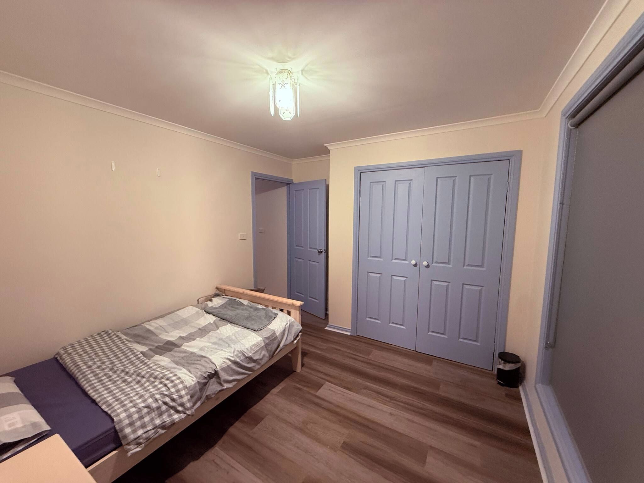 A bedroom with a single bed, a wardrobe, and a door.