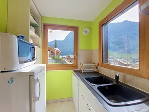 A compact kitchen with a window view of a mountain landscape, a microwave, a sink, and a drying rack. - Chalet Pelou - 7 peoples - Morzine (Morzine)