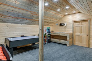 Ein Zimmer mit Billardtisch, Spielkonsole und einer Tür.
