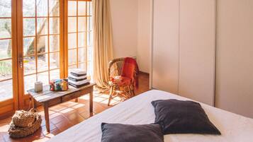 A bedroom with a bed, a chair, a table, and a window.