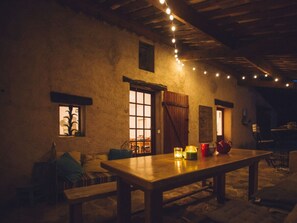 A rustic interior with a wooden table, benches, and string lights. - MAS DU Perigoulier (Cotignac)