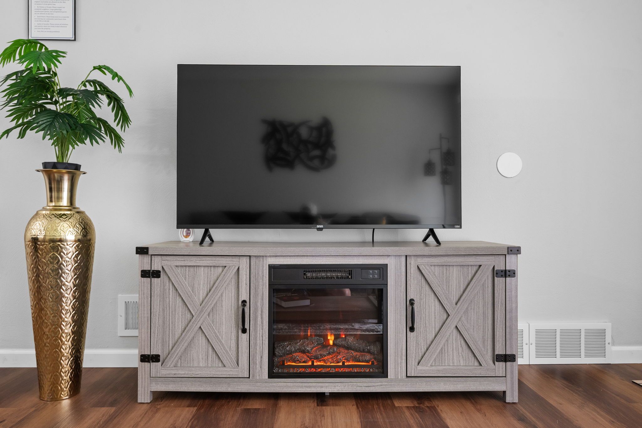 A modern entertainment unit with a flat-screen TV, a fireplace, and a decorative vase.