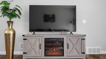 A modern entertainment unit with a flat-screen TV, a fireplace, and a decorative vase.