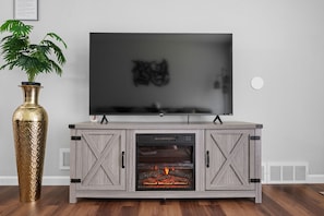 Een moderne entertainmentkast met een flatscreen televisie, een open haard en een decoratieve vaas.