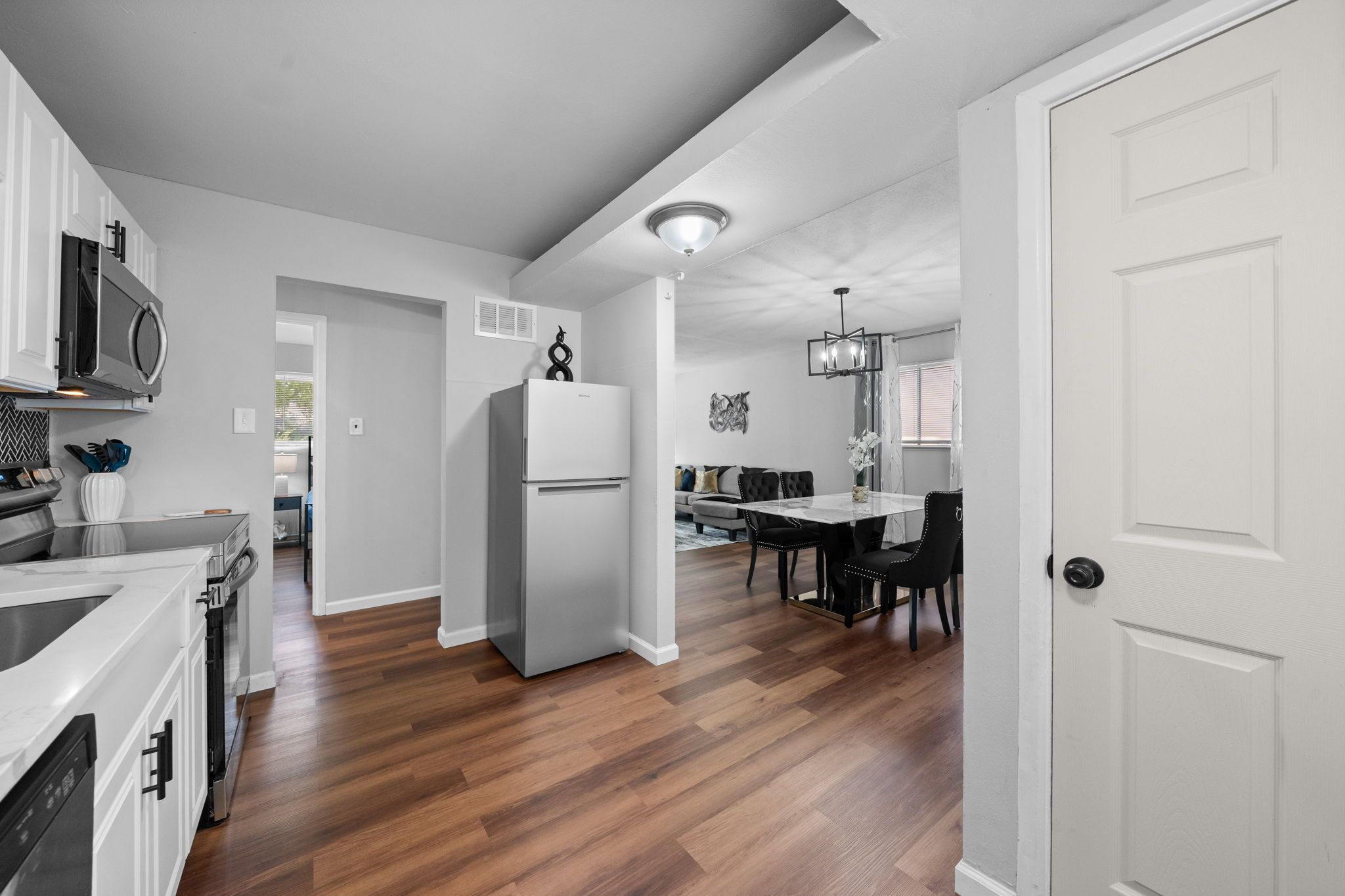 A modern kitchen with white cabinets, a built-in microwave, and a large refrigerator.