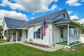 A single-story house with a dark roof, a front porch, and an American flag. - 1 Mi to Downtown! Cute Cambridge Getaway (Cambridge)