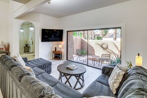 A living room with a sofa, a coffee table, and a TV mounted on the wall. - Sip, Soak & Stargaze: Palm Desert Retreat! (Palm Desert)
