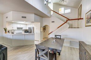 A spacious kitchen with a central island, a dining area with a wooden table, and a staircase leading to an upper level. - Sip, Soak & Stargaze: Palm Desert Retreat! (Palm Desert)