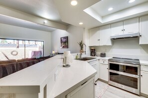 A modern kitchen with a large island, built-in appliances, and a view to the outside. - Sip, Soak & Stargaze: Palm Desert Retreat! (Palm Desert)
