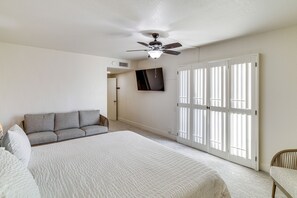 A bedroom with a bed, a sofa, a ceiling fan, a TV, and a door with blinds. - Sip, Soak & Stargaze: Palm Desert Retreat! (Palm Desert)