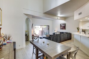 A modern interior with a dining area, a living room with a sofa, and a kitchen. - Sip, Soak & Stargaze: Palm Desert Retreat! (Palm Desert)