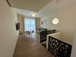 A modern living room with a dining area, a sofa, and a TV mounted on the wall. - Blue Wave Apartment: Relax by the Sea, Panoramic Terrace, and Modern Design (Letojanni)