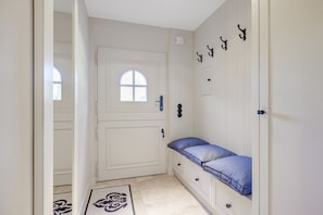 A narrow hallway with a white door, a small window, and a bench with blue cushions. - Large Artists' Studio, Apt. 14, in the Witthüs—The “large artists’ studio,” in a prime (Wenningstedt-Braderup (Sylt))