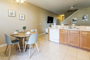Eine Küche mit Esstisch, Stühlen, Geschirrspüler und Deckenventilator.