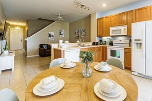 Une cuisine moderne avec des meubles en bois, une table à manger dressée avec de la vaisselle blanche et une machine à café.