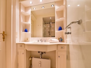 A bathroom with a large mirror, a sink, a shower, and a radiator. - Holiday Apartment Oystercatcher (Kampen)