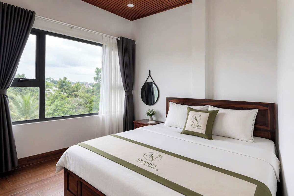 Una camera d'albergo con un letto grande, vista sul verde circostante e soffitto in legno.