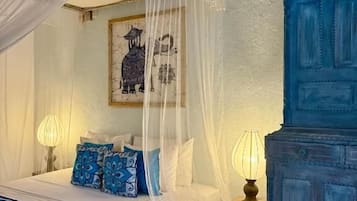 Une chambre à coucher avec un lit à baldaquin, une commode bleue et une table de chevet avec une lampe.