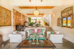A spacious living area with a high ceiling, a staircase leading to an upper level, and a fireplace.