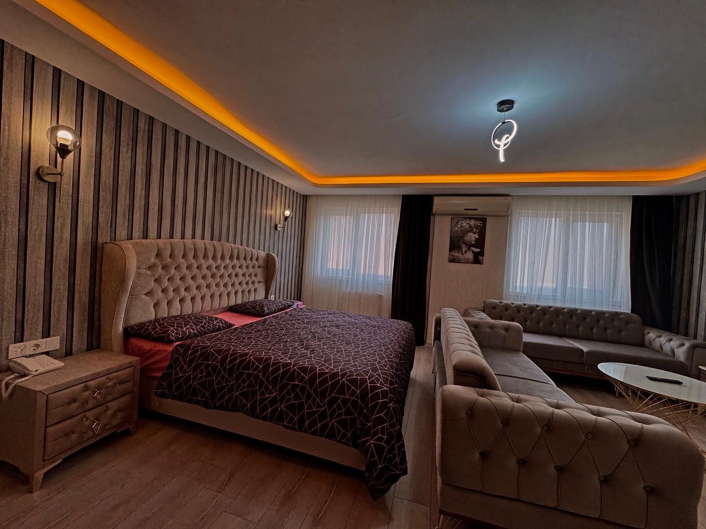 A modern bedroom with a large bed, a sofa, a small table, and a nightstand.