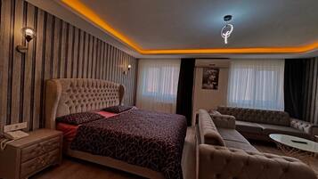 A modern bedroom with a large bed, a sofa, a small table, and a nightstand.