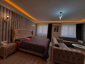 A modern bedroom with a large bed, a sofa, a small table, and a nightstand.