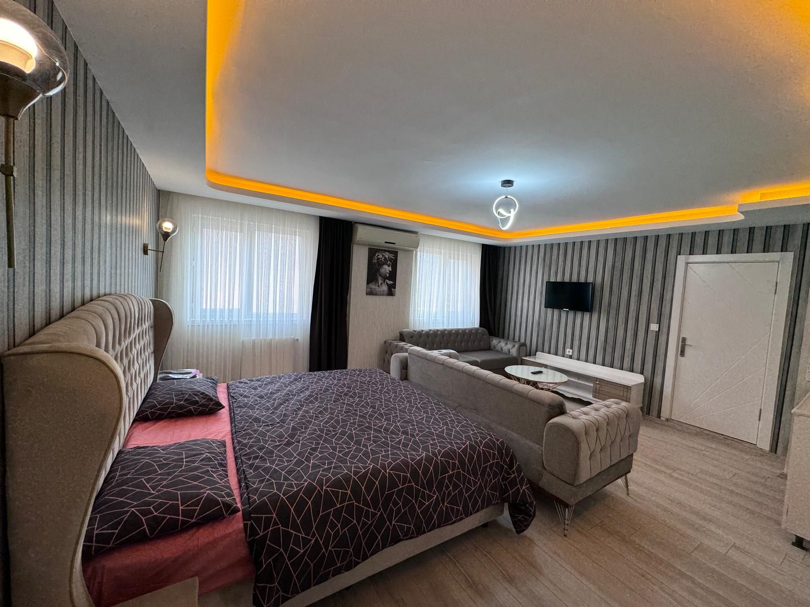 Un dormitorio moderno con cama, sofá y televisor.