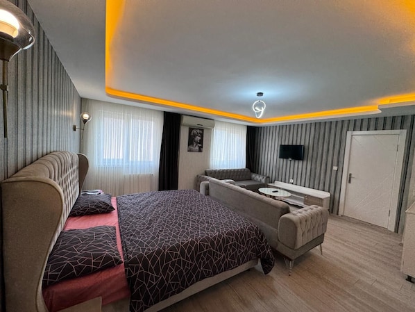 Un dormitorio moderno con cama, sofá y televisor.