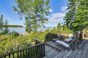 A wooden deck with outdoor furniture overlooking a lake.