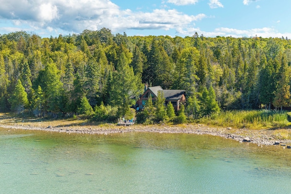 Eine Hütte am See mit Steg und Stühlen.