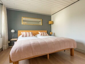 A bedroom with a bed, a nightstand, a lamp, and a mirror on the wall. - Holiday Home in Renesse With Swimming Pool (Renesse)