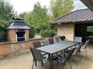 An outdoor patio with a brick barbecue area, a grill, and a table with chairs. - Holiday Home Kissner (Ilsenburg)