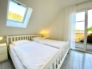 A bedroom with a bed, a nightstand, a lamp, a window, and a view of the outdoors. - Holiday Home Kissner (Ilsenburg)