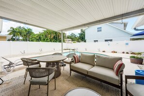Ein überdachter Patio-Bereich mit Pool, Gartenmöbeln und Blick auf die Nachbarschaft.