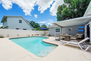Ein Garten mit Swimmingpool, einer überdachten Terrasse und einem Haus.