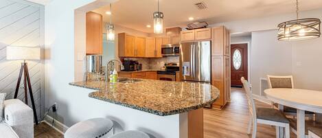 Cocina moderna con encimeras de granito, electrodomésticos de acero inoxidable y armarios de madera.
