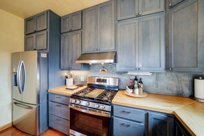 Une cuisine équipée d’un réfrigérateur en acier inoxydable, d’une cuisinière et de meubles de rangement en bois.