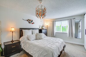 Une chambre à coucher avec un lit, des lampes de chevet, une table de chevet, un miroir et une fenêtre avec des rideaux.