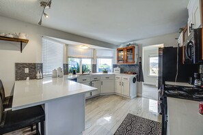 A modern kitchen with a central island, white cabinetry, and a black refrigerator. - Seasonal Private Pool: Tacoma Home w/ Patio & BBQ! (Tacoma)