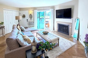 A living room with a sofa, ottoman, and a flat-screen TV. - Flatiron Views, Pool Access! Boulder Extended Stay (Boulder)