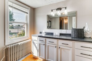 A kitchen with white cabinets, a black countertop, and a window with blinds. - Walk to Dining & Brewery! Cozy Kiel Apartment (Kiel)