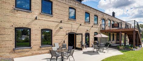 A brick building with a patio area featuring outdoor seating and a covered section.