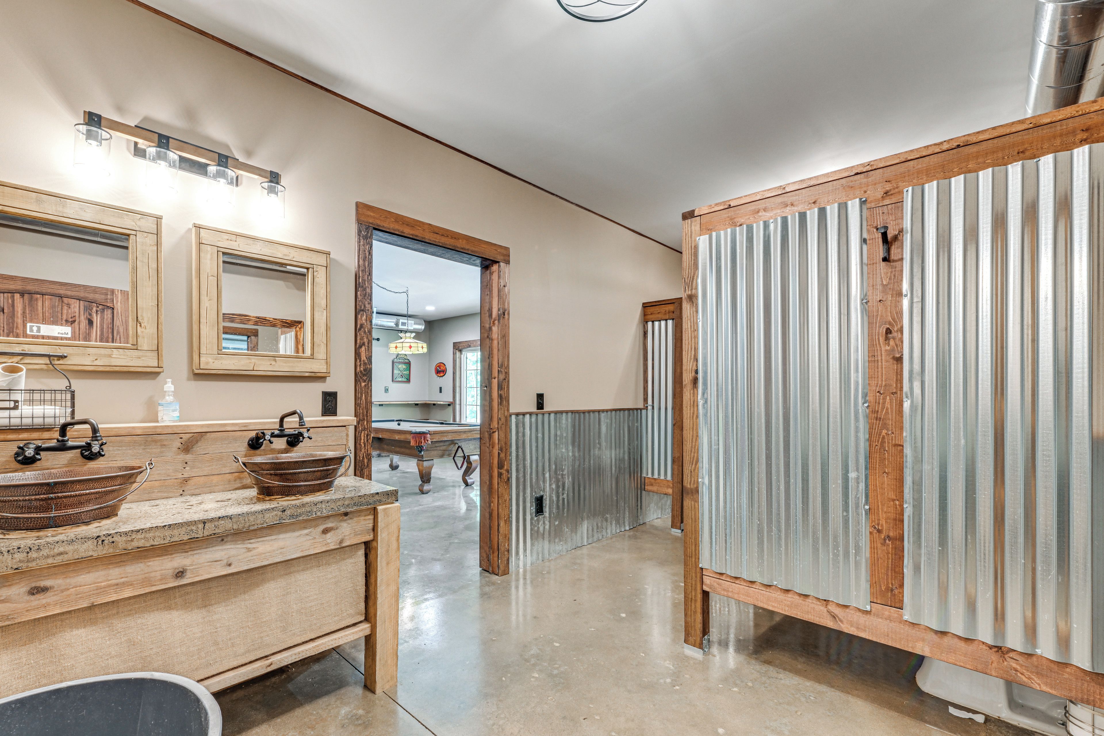 Un couloir avec un banc en bois, un miroir à cadre métallique et une porte à cadre métallique.