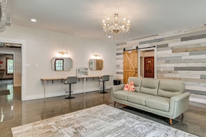 Een modern interieur met een kroonluchter, een bank en een wand met een houten paneelstructuur.